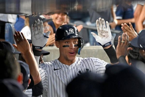 Aaron Judge is greeted by his Yankees teammates in the dugout.